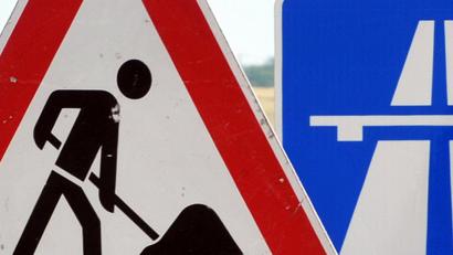 Bild: Martin Schutt/dpa
Ein Baustellenschild vor einem Autobahnschild.