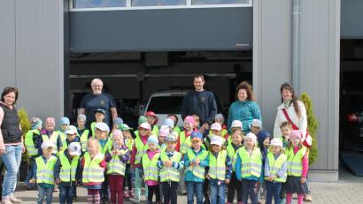 Bild: exb
Die Kindergartenkinder in der Autowerkstatt, wo sie mit  Sicherheitswarnwesten ausgestattet wurden.