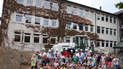 Bild: Thomas Dobler
Im Hintergrund der sanierungsbedürftige A-Bau der Schule, vorne Erwachsene, die für den Umbau verantwortlich sind, und Grundschüler, die in den Genuss der Modernisierung kommen werden.