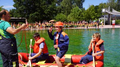 Bild: BKR
Die Jugendfeuerwehr holt Lea Wolf von ihrer letzten Gruppenstunde bei den Feuerdrachen ab. Sie erhält gleichzeitig die Einsatzbekleidung der Jugendfeuerwehr. Das Boot bringt sie auf die andere Beckenseite.