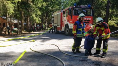 Bild: MDE
In sicherer Entfernung warten die Waldbären, bis ihre Kameraden gemeinsam mit den Feuerwehrleuten den „Waldbrand“ bekämpft haben.