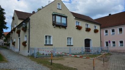 Bild: jr
In dem abgesperrten Bereich vor dem Resl-Haus stand bis vor kurzem noch eine stattliche Linde. Der Baum musste laut Marktgemeinde gefällt werden, weil Wurzeln in den Kanal eingewachsen waren.