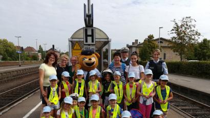 Bild: Bundespolizei
Der Ausflugstag des Kindergartens St. Dionysius Neunkirchen beginnt nicht gut: Der ursprüngliche Zug ist schon abgefahren. Dafür fährt die Bundespolizei mit Toni, dem Bären, unterhaltsame Geschütze auf. Für enttäuschte Gesichter bleibt da keine Zeit. So spannend kann Warten sein.