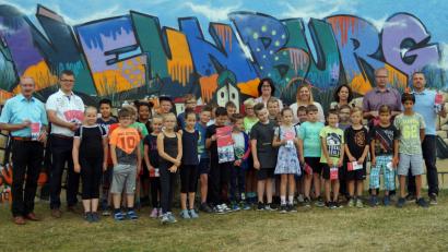 Bild: agr
Genauso bunt, wie die Graffitiwand am Schulgebäude, sind auch die Veranstaltungen im Ferienprogramm. Die neue Auflage präsentierten die Bürgermeister Albert Krieger (Bodenwöhr) und Martin Birner (Neunburg, von links) sowie Jugendbeauftragter Harald Klatzka, ArGe-Jugend-Vorsitzender Georg Keil, Schulleiterin Sabine Bauer und die Verwaltungsmitarbeiterinnen Martina Greiner und Elisabeth Lottner (von rechts), zusammen mit mehreren Kindern.