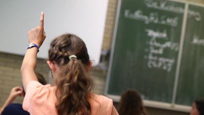 Bild: Daniel Karmann/dpa
Eine Schülerin hebt im Unterricht den Finger.