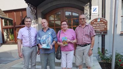 Bild: gi
Bürgermeister Hermann Ach (links) dankt Roland Watzke für 20 Mal Moosbach sowie Rita Horina und Horst Weber für den zehnten Aufenthalt mit einem kleinen Präsent.