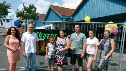 Bild: rn
Ein breites Band wirbt für die neue Firma. Marita Gradl vom Gewerbeverein und zweiter Bürgermeiste rKarl Lorenz (von links) gratulierten mit Sekt der Familie Neifert (von links Dennis, Vera, Viktor, Elena und Julia) zur Geschäftseröffnung.