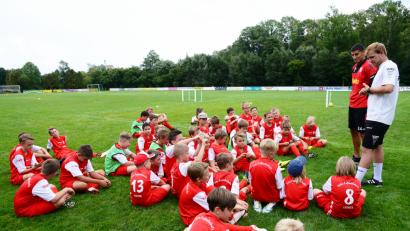Bild: bey
Fußballprofi Ali Odabas (stehend, Zweiter von rechts) beantwortet auf dem Rasen des TSV-Platzes in einer "kleinen Pressekonferenz" die Fragen der Kinder.