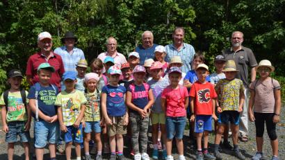 Bild: jr
21 Kinder erwandern den rund 2,8 Kilometer langen Waldbesinnungspfad. Mit dabei sind Pfarrseelsorger Pater Benedikt Leitmayr (rechts), zweiter Bürgermeister Reinhard Wurm (Zweiter von rechts) und Rauchclub-Vorsitzender Gottfried Richtmann (Dritter von rechts).