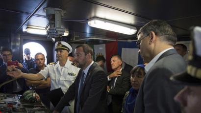 Bild: Mohamed Ben Khalifa/AP/dpa
Matteo Salvini (Mitte), Innenminister von Italien, hört dem Kapitän eines Schiffes der italienischen Marine zu, der ihm auf der Brücke des Schiffes in der Marinebasis von Tripolis die Aufgaben erklärt.