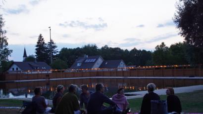 Bild: mmj
Ein ruhiger Platz auf der Liegewiese, bunte Lichter spiegeln sich im Wasser. Ein gemütliches Ambiente beim Sommerfest am Moorbadgelände.