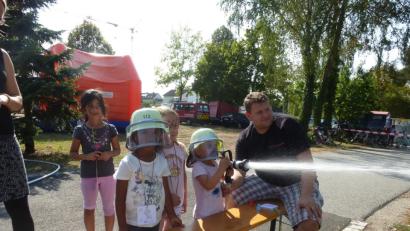 Bild: bk
Die vierjährige Mia kann kaum den Feuerwehrschlauch greifen. Aber sie schafft es, das "Feuer" im Übungshäuschen zu löschen. Lena und Isabel schauen ihr zu.