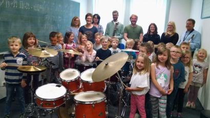 Bild: kwl
Die Leiterin des Kindergartens „St. Martin“, Theresa Uhl (stehend, Zweite von links) ist wie die Kids von den verschiedenen Instrumenten begeistert. Flugs schwingt sie sich aufs Drumset und zeigt den Kleinen ihre vielfältigen musikalischen Fähigkeiten.