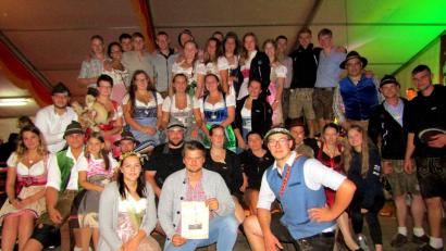 Bild: sck
Fabian Lessau hält das Bild des Kirwabaums in den Händen, den er gewonnen hat. Mit ihm freuen sich die Wellucker Kirwaleit'.