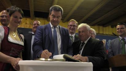 Bild: exb
Zum Abschluss seines Besuches in Guteneck trug sich der bayerische Ministerpräsident Markus Söder ins Goldene Buch der Gemeinde ein, das Bürgermeister Johann Wilhelm (vorne rechts) mit in den Gutsstadel des Schlosses gebracht hatte.