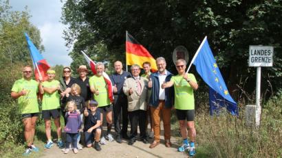 Bild: pi
Mit der europäischen Fahne sowie den Flaggen aus Polen, der Tschechischen Republik und Deutschlang überqueren die Läufer mit Mariusz Szeib (rechts) die Grenze in Waldheim und freuen sich über den Empfang durch Bürgermeister Johann Maurer (Zweiter von rechts).