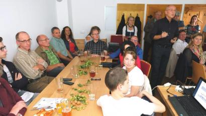 Bild: do
Eingebettet in ein Zoigl-Fest informierten im Dammbauernhaus Stadtpfarrer Thomas Jeschner und Architekt Armin Juretzka (stehend, Zweiter von rechts) über die Gründe zum Verkauf des alten Pfarrheimes und die ersten Planungen für den Neubau auf dem Grundstück des ehemaligen Feuerwehrhauses.