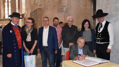 Bild: cr
Josef Hauer trägt sich ins Stiftungsbuch ein. Über die Schulter schauen ihm (von links) der Übersetzer in Egerländer Tracht, Ulrika Hart, Bürgermeister Michal Pospísil, Konrad Dippel, Rainer Christoph, Bürgermeisterin Tanja Schiffmann und Karl Müller.