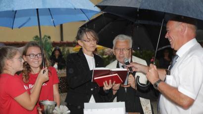 Bild: Wolfgang Steinbacher
Trotz eines heftigen Gewittergusses lassen sich die Ministrantinnen (links) und Bürgermeister Roland Strehl (rechts) bei der Einweihung der neuen Theuerner Brücke den Spaß nicht verderben. Pfarrerin Birgit Schwalbe-Eberius und Ruhestandsgeistlicher Josef Beer übernehmen den kirchlichen Part.