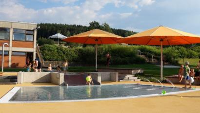 Bild: weu
Die jungen Familien sind voll des Lobes über den neuen Kleinkindbereich im Freibad Oberviechtach. Die zwei Becken sind mit einer Rutsche verbunden, Fontänen und ein Seelöwe lassen das Wasser sprudeln. Die Eltern können die Sitz- und Liegepodeste am Beckenrand nutzen, beschattet von zwei riesigen Schirmen.