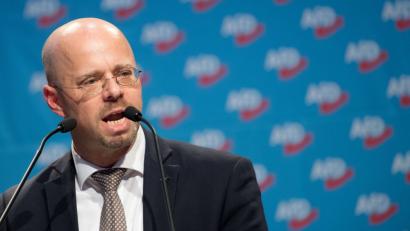 Bild: Julian Stratenschulte/dpa
Andreas Kalbitz, Beisitzer im AfD-Bundesvorstand, hier beim Bundesparteitag vergangenes Jahr in Hannover, macht sich am Tag der Deutschen Einheit in Mantel über "Schmierenblätter", "Altparteien" und "Multikulti-Spinnerei" lustig.