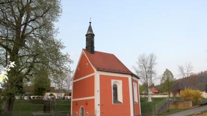 Bild: boj
Die Wieskapelle „Zum gegeißelten Heiland“ in der Parkanlage des Friedhofs: Eine mächtige Linde, die wohl so alt ist wie die Kapelle (265 Jahre), steht wie eine Beschützerin vor dem Bauwerk.