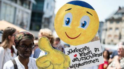 Bild: Federico Gambarini/dpa
Eine junge Frau trägt auf dem Marktplatz in Bonn ein Schild mit der Aufschrift "Jüdisches Leben in Deutschland willkommen".. Mehrere hundert Menschen demonstrieren an diesem Tag gegen Antisemitismus.