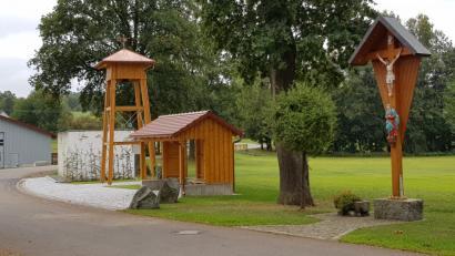 Bild: dob
Dorfkreuz, Bushäuschen und Glockenturm bilden ein Ensemble in der Dorfmitte von Unterlind. Allerdings ist der Glockenturmbau noch nicht von allen akzeptiert.