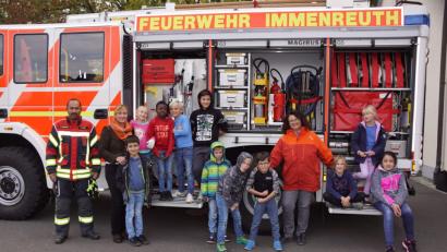 Bild: bkr
Claudia Schleicher (Vierte von rechts)) und Nadine Manhart (Zweite von links) besuchen mit der Offenen Ganztagsschule die Feuerwehr. Zweiter Kommandant Christopher Hörl (links) zeigt seinen jungen Gäste auch das Löschfahrzeug.