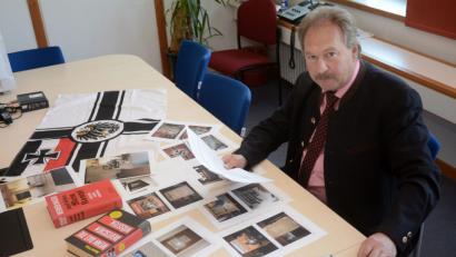 Bild: Schönberger
Johann Brandl leitet das Kommissariat 5. Vor ihm liegen Fundstücke von Durchsuchungen, darunter ein Handbuch für Reichsbürger („Wenn das die Deutschen wüssten“) oder auch Hitlers „Mein Kampf“ mit Kommentaren. 	Bild: Schönberger