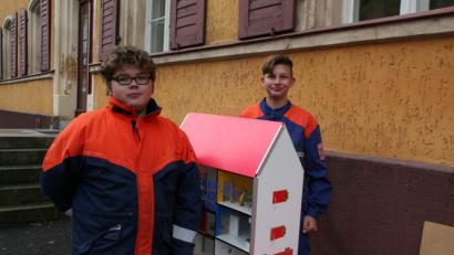 Bild: wfw
Anhand des Rauchmelderhauses demonstrieren zwei Feuerwehranwärter anschaulich die Funktionsweise eines Rauchmelders bei einem Zimmer- oder Wohnhausbrand.