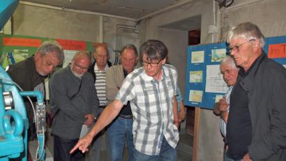 Bild: sön
Kraftwerksbetreiber Karl Senft (Dritter von rechts) erläutert im Turbinenhaus die Wirkungsweise der Wasserkraftanlage.