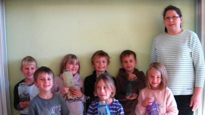 Bild: gi
Leer Kaffeegläser erhalten hübsche Motive durch die Serviettentechnik. Die Kinder sind mit Betreuerin Silke Krämer stolz auf ihre schönen Windlichter.