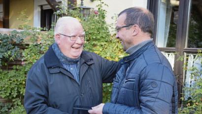 Bild: exb
Mesner Siegfried Stock (rechts) übergibt Pfarrer Siegfried Wölfel das Handy von Peter Lehmeier.