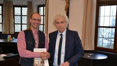 Bild: rti
Landrat Wolfgang Lippert (rechts) überreicht an Ely Eibisch die Kommunale Dankurkunde und den 30. Band der Buchserie „Heimat – Landkreis Tirschenreuth“.