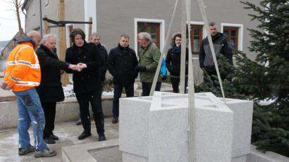 Bild: Lowak
Künstler Harald Bäumler (Dritter von links) und Architekt Josef Schöberl (Zweiter von links) beobachten am Neuhauser Marktplatz, wie der Zoiglstern aus Granit millimetergenau angepasst wird.