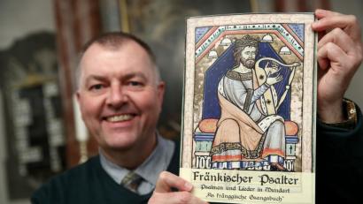 Bild: agentur_dpa
Pfarrer Claus Ebeling hält das Kirchliche Mundart-Gesangbuch "Fränkischer Psalter - Psalmen und Lieder in Mundart - As fränggische Gsangsbuch" in der Dreieinigkeitskirche in den Händen. Das spezielle Gesangbuch für Franken beinhaltet nicht nur das fränkische "Vaterunser", sondern insgesamt 23 biblische Psalmen und 44 Lieder auf 80 Seiten. Darunter auch Dialekt-Fassungen von bekannten Weihnachtsliedern.