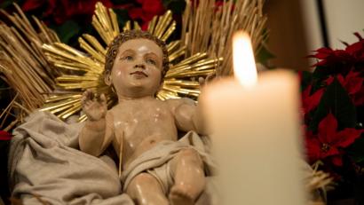 Bild: Sven Hoppe/dpa
In einer Krippe liegt eine Holzfigur von Jesus. Daneben brennt eine Kerze.