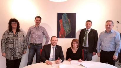 Bild: fjo
Bürgermeisterin Margit Kirzinger (sitzend, rechts) und Enrico Delfion (sitzend, links) unterzeichnen den Breitband-Vertrag.