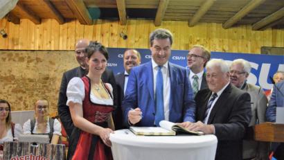 Bild: mp
Beim CSU-Sommerempfang in Guteneck trägt sich Ministerpräsident Markus Söder ins Goldene Buch der Gemeinde ein.