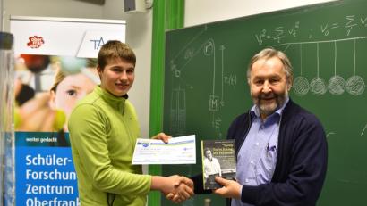 Bild: exb
Mit einer Ehrenurkunde und einem autobiographischen Buch von Nobelpreisträger Richard P. Feyman würdigt Professor Walter Zimmermann (rechts) das Abschneiden von Lorenz Märker vom Gymnasium Eschenbach beim Regionalentscheid der Jungphysiker.