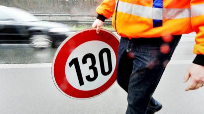 Bild: Marius Becker/dpa
Ein Mitarbeiter der Autobahnmeisterei trägt auf der Autobahn 661 bei Frankfurt ein Schild zur Höchstgeschwindigkeit von 130 Stundenkilometern.