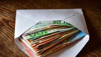 Bild: Patrick Pleul/ZB/dpa
Mehrere Eurobanknoten liegen in einem Briefumschlag auf einem Tisch.