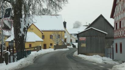 Bild: fjo
Bei der Hauberrisser-Kapelle (im Hintergrund) zweigt von der Dorfstraße die Burkhardsriether Straße ab. Direkt beim Fachwerkhaus (rechts) liegt die Einmündung zum Dorfplatz, der sich am Ende in Zimmerschlag- und Christmettenweg aufsplittet.