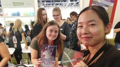 Bild: Nicole Alfa/privat
Bei einer Signierstunde auf der Leipziger Buchmesse, zusammen mit der Schwester einer Bloggerfreundin. Sie hat die Postkarte, die sie in der Hand hält, für Nicole gestaltet.