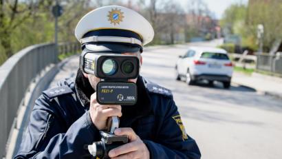 Bild: Matthias Balk/dpa
Ein Polizist misst die Geschwindigkeit vorbeifahrender Fahrzeuge mit einer Laserpistole.