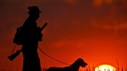 Bild: Patrick Pleul
ILLUSTRATION - Ein steht mit seinem Hund im Sonnenuntergang auf einem Feld. Foto: Patrick Pleul/Archiv