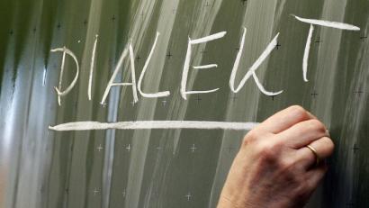 Bild: Daniel Karmann
Eine Frau schreibt das Wort "Dialekt" auf eine Tafel. Foto: Daniel Karmann/Archiv