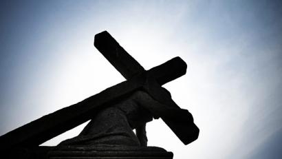 Bild: Nicolas Armer/dpa
Unter blauem Himmel und gegen die Sonne zeichnet sich eine Jesusstatue unter dem Kreuz ab.