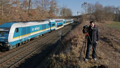 Bild: tr
Korbinian Eckert auf der "Jagd". Mit dem Smartphone checkte er vorher, ob der "Alex" den Wiesauer Bahnhof pünktlich verlassen hat. Dann wusste er, dass es noch sieben Minuten dauert, bis der Zug an seinem Standpunkt vorbeikommt. Die Kamera steht fest auf dem Stativ, Blende und Verschlusszeit sind eingestellt. Normalerweise fotografiert Eckert natürlich mit Blickrichtung auf den Zug. Für unsere Kamera macht er eine Ausnahme.